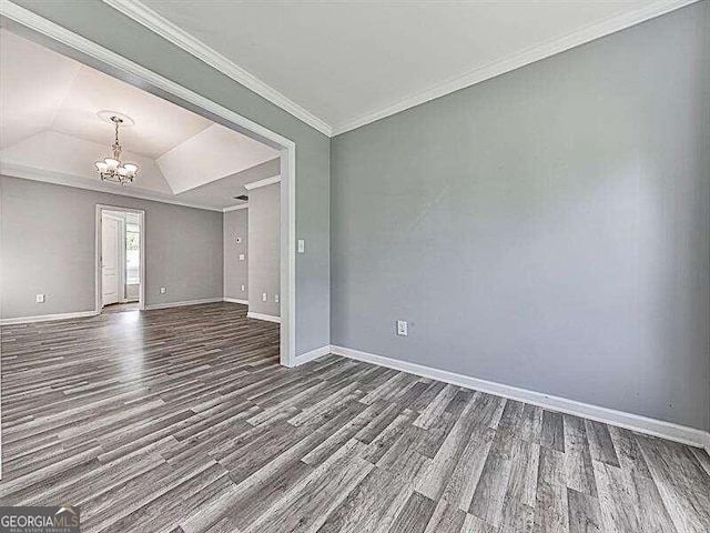 empty room with a raised ceiling, a chandelier, ornamental molding, and hardwood / wood-style flooring