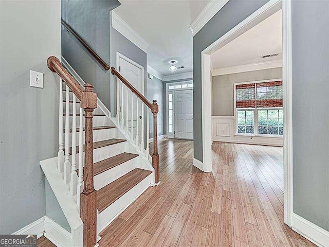 stairs with hardwood / wood-style flooring and crown molding