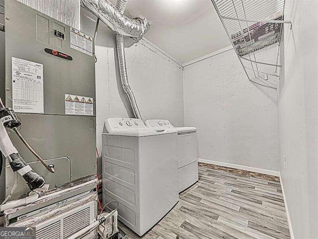 laundry area featuring light hardwood / wood-style floors, heating unit, and washing machine and clothes dryer