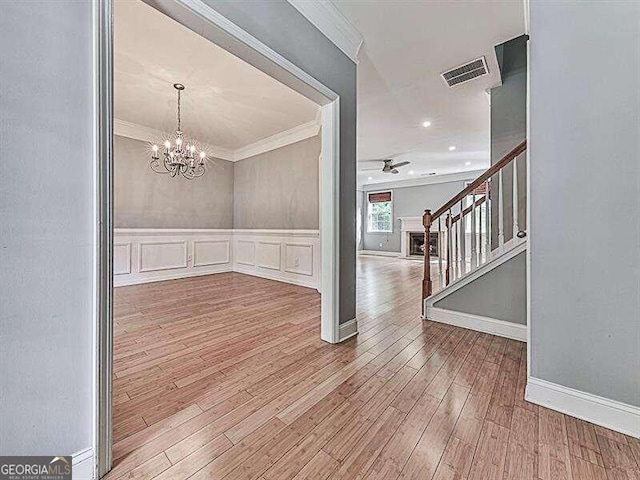 entrance foyer with ceiling fan with notable chandelier, hardwood / wood-style flooring, and crown molding