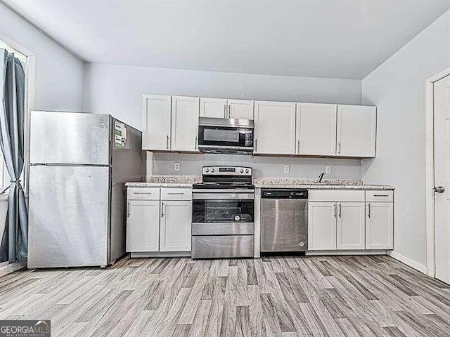 kitchen with appliances with stainless steel finishes, light hardwood / wood-style flooring, and white cabinets