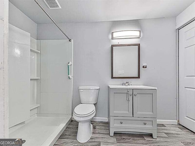 bathroom with toilet, a shower, vanity, and wood-type flooring