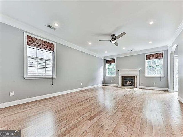 unfurnished living room featuring ceiling fan, light hardwood / wood-style floors, a healthy amount of sunlight, and ornamental molding