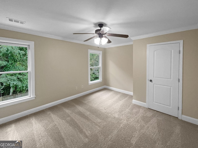 carpeted empty room featuring baseboards, a ceiling fan, visible vents, and crown molding