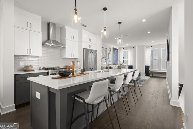 kitchen featuring high quality fridge, a large island, wall chimney exhaust hood, and dark hardwood / wood-style floors