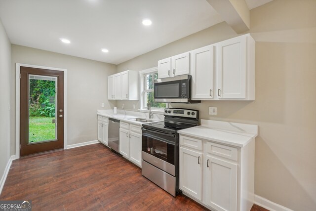 kitchen featuring sink, dark hardwood / wood-style flooring, light stone counters, stainless steel appliances, and white cabinets