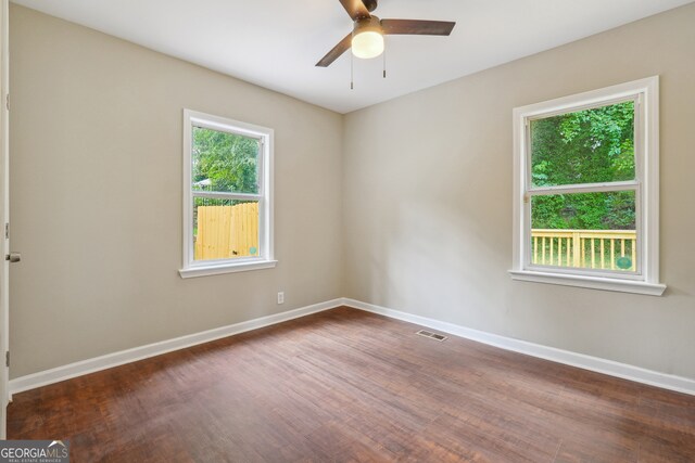 unfurnished room with ceiling fan, dark wood-type flooring, and a healthy amount of sunlight