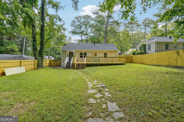 rear view of house featuring a wooden deck and a yard