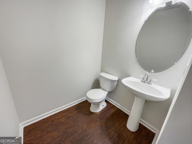 half bathroom featuring toilet, baseboards, and wood finished floors