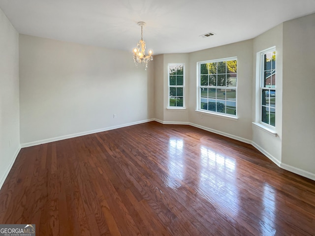 unfurnished room featuring an inviting chandelier, baseboards, and dark wood finished floors