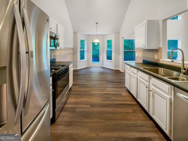 kitchen featuring appliances with stainless steel finishes, dark countertops, a sink, and lofted ceiling