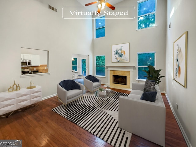 living area featuring baseboards, visible vents, ceiling fan, wood finished floors, and a high end fireplace