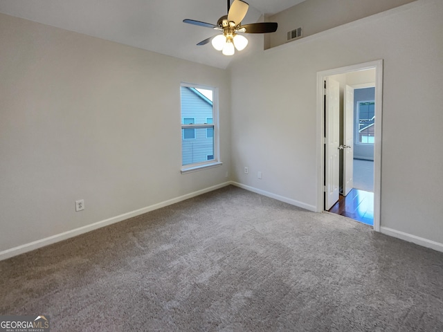 carpeted spare room featuring lofted ceiling, a ceiling fan, visible vents, and baseboards