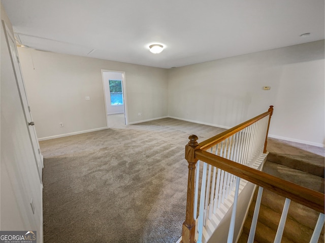 carpeted spare room with attic access and baseboards