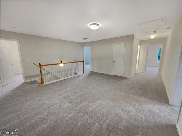 carpeted spare room featuring attic access, visible vents, and baseboards