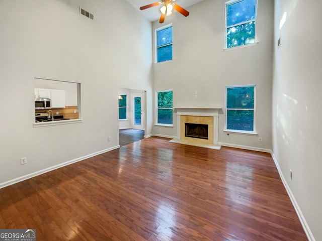 unfurnished living room with dark wood-style floors, a healthy amount of sunlight, visible vents, and a fireplace