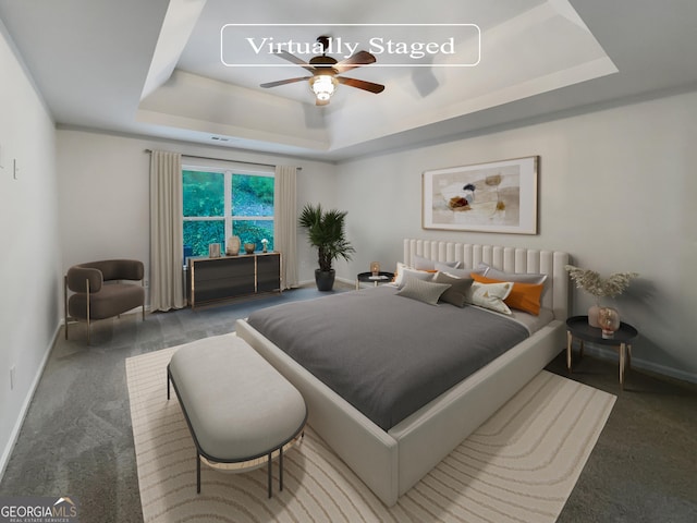 carpeted bedroom featuring ceiling fan, a tray ceiling, and baseboards