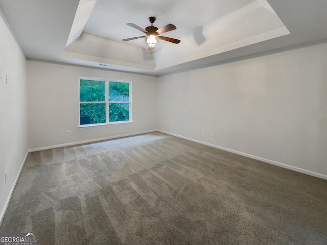 spare room with carpet floors, ceiling fan, baseboards, and a raised ceiling