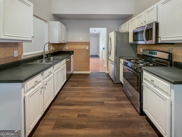 kitchen featuring stainless steel appliances, dark countertops, dark wood-type flooring, and a sink