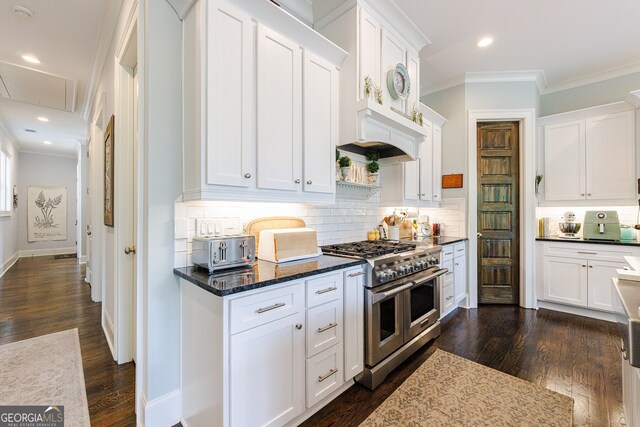 kitchen featuring backsplash, range with two ovens, dark hardwood / wood-style flooring, crown molding, and white cabinets