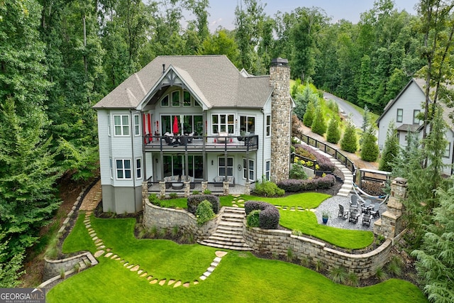 back of property featuring a wooden deck, a patio area, and a yard