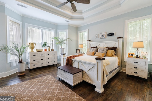 bedroom featuring ceiling fan, dark hardwood / wood-style floors, a tray ceiling, and ornamental molding