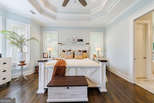 bedroom with dark wood-type flooring, ceiling fan, crown molding, and a tray ceiling