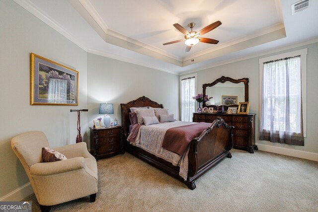 carpeted bedroom with ceiling fan, a tray ceiling, and ornamental molding