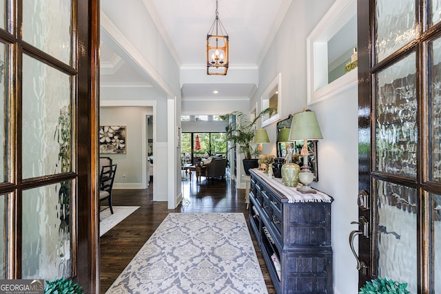 entrance foyer with a chandelier, crown molding, and dark hardwood / wood-style floors