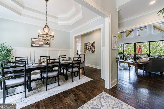 dining area featuring a raised ceiling, dark hardwood / wood-style flooring, ornamental molding, and a notable chandelier