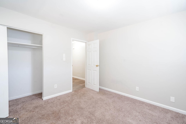 unfurnished bedroom with light carpet, baseboards, and a closet