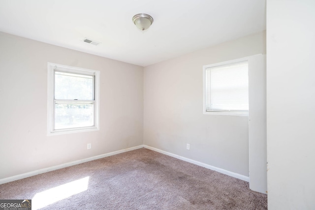 unfurnished room featuring carpet flooring, visible vents, and baseboards