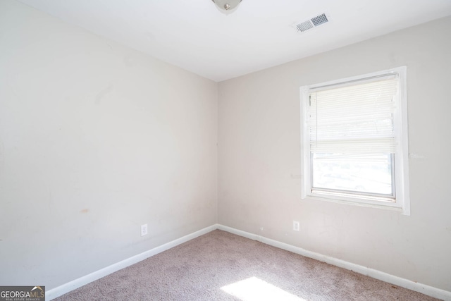 empty room with carpet, visible vents, and baseboards