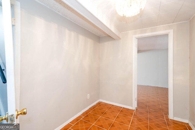 hallway with an inviting chandelier, baseboards, and tile patterned floors