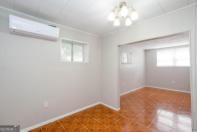 spare room featuring a wall unit AC, an inviting chandelier, and baseboards