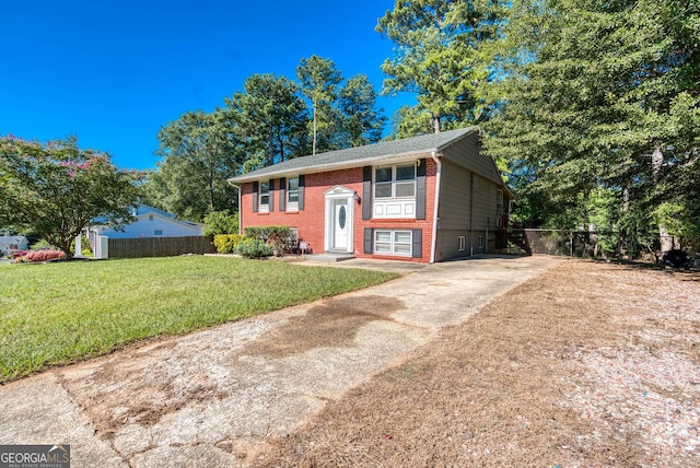 split foyer home featuring a front yard, fence, concrete driveway, and brick siding