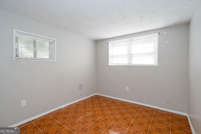 unfurnished room featuring plenty of natural light, baseboards, and a textured ceiling