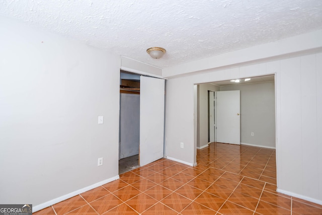 unfurnished room featuring tile patterned flooring, baseboards, and a textured ceiling