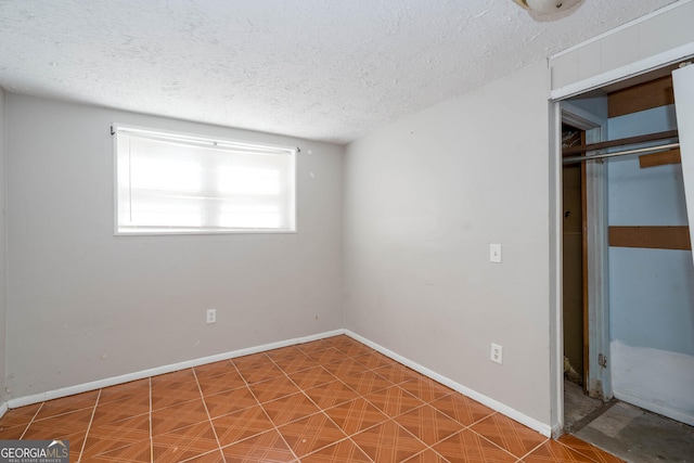 unfurnished bedroom with a closet, a textured ceiling, and baseboards