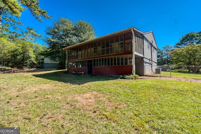 rear view of house featuring a sunroom, fence, and a yard