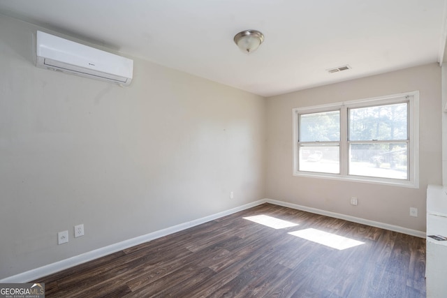 unfurnished room featuring dark wood-type flooring, a wall unit AC, visible vents, and baseboards