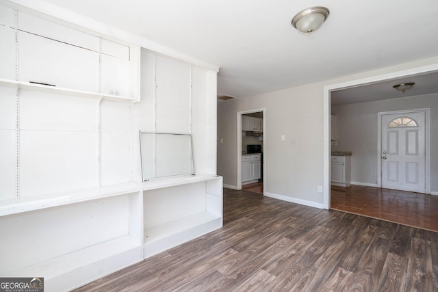 empty room featuring baseboards and dark wood-style flooring