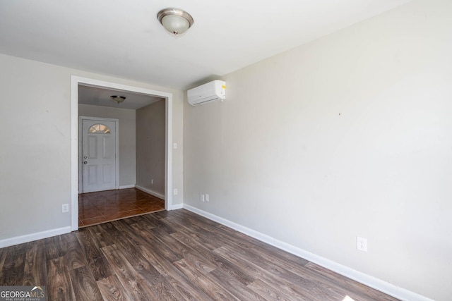 unfurnished room with a wall unit AC, baseboards, and dark wood-style flooring