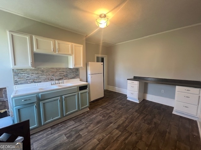 kitchen with backsplash, dark hardwood / wood-style flooring, white fridge, sink, and crown molding