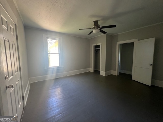 unfurnished bedroom featuring ornamental molding, a textured ceiling, dark hardwood / wood-style flooring, a closet, and ceiling fan