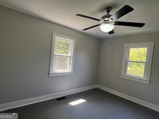 empty room with a wealth of natural light, hardwood / wood-style flooring, and ceiling fan