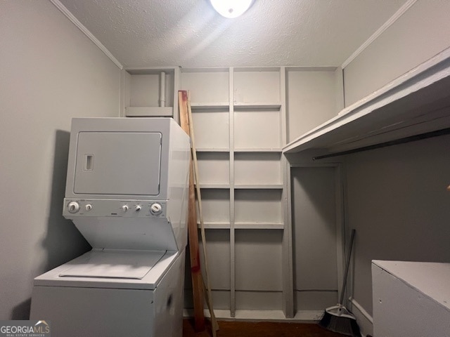 laundry room featuring crown molding, stacked washer and dryer, and a textured ceiling