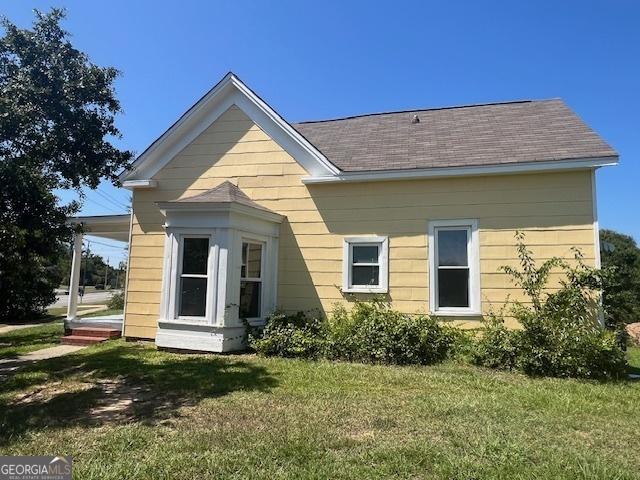 rear view of property with central AC and a yard