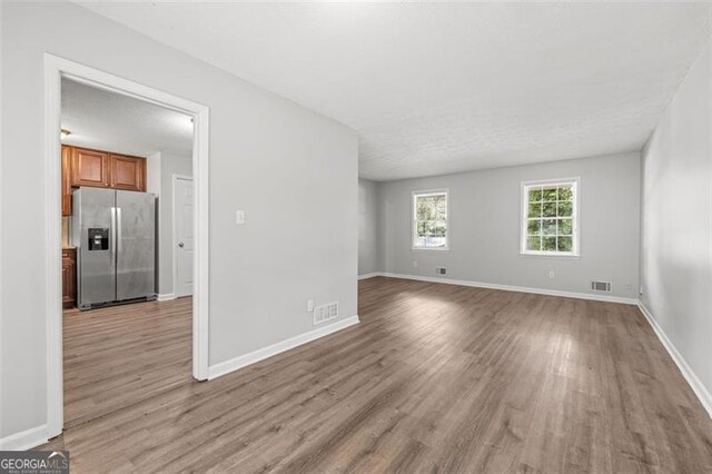 unfurnished room featuring visible vents, baseboards, and wood finished floors