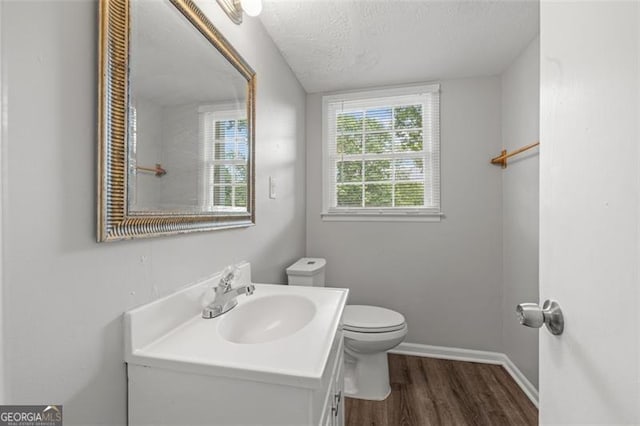 bathroom with toilet, a textured ceiling, wood finished floors, baseboards, and vanity